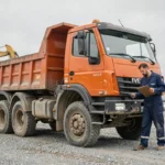 Mécanicien inspectant un camion benne Iveco d'occasion sur un chantier de construction